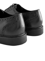 Pair of black leather brogue shoes on a white background