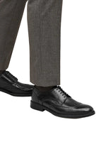 Black dress shoes worn with gray trousers on a white background