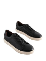 Pair of black leather sneakers on a light gray background