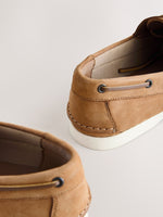 Close-up of brown suede shoes with white soles on a light background