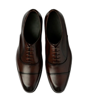Pair of brown leather dress shoes on a light gray background