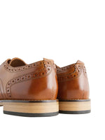 Pair of brown leather shoes with wooden soles on a light gray background