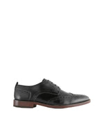 Black leather brogue shoe on a light gray background