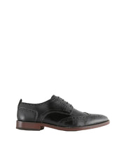 Black leather brogue shoe on a light gray background