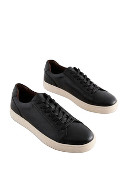 Pair of black leather sneakers on a light gray background