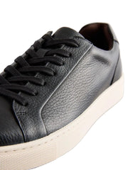 Black leather sneakers with white soles on a light gray background