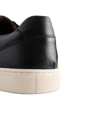 Black leather shoes with white soles on a light gray background
