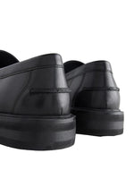 Black leather shoes with thick soles on a light background