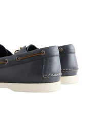 Pair of navy blue leather boat shoes on a light gray background