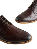 Pair of brown leather brogue shoes on a light background