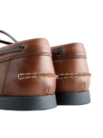 Pair of brown leather shoes with black soles on a light background