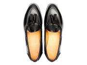 Luxury men's black leather slip-on loafers with tassel detailing and leather lining.